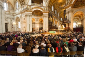 A large crowd sits inside a St. Pauls cathedral attending a school service.