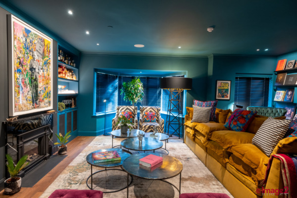 Eclectic room with teal walls, a mustard sofa, zebra chairs, a colorful painting, and metal coffee tables.