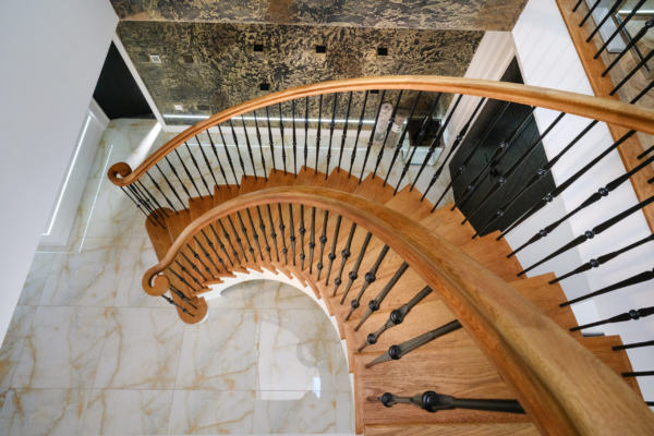 High-angle view of a dramatic, spiral wooden staircase with glass railings in a modern building.