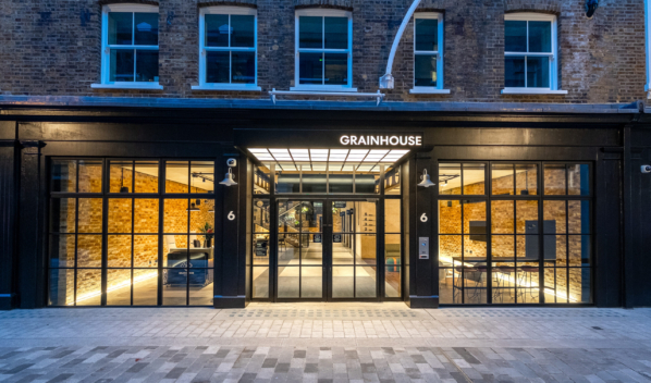 Exterior front of "Grainhouse" with black framing, large windows, and warm interior lighting.