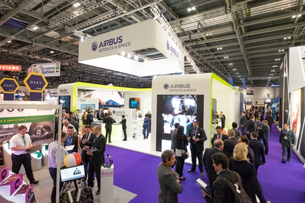 A busy exhibition hall featuring a large, modern "Airbus Defence &amp; Space" stand with many attendees.