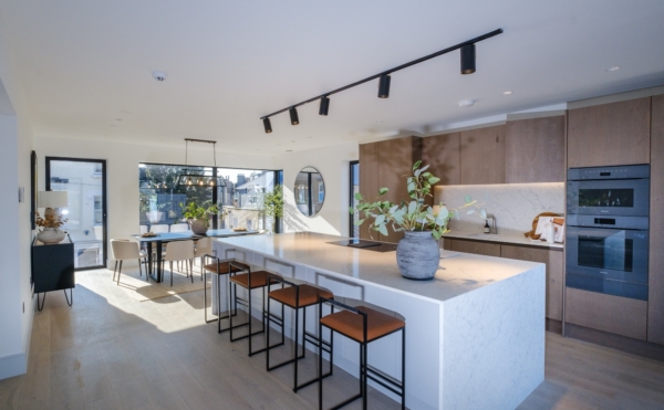 Bright modern open-plan kitchen and dining area with a large marble island, barstools, and ample natural light