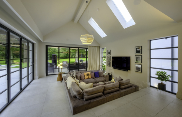 Bright, high-ceilinged living room with skylights, a large modular sofa, and expansive sliding glass doors.