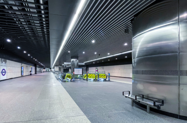 Elizabeth Line . A wide, curved subterranean subway platform tunnel with bright white lighting panels. Spaceous Platform